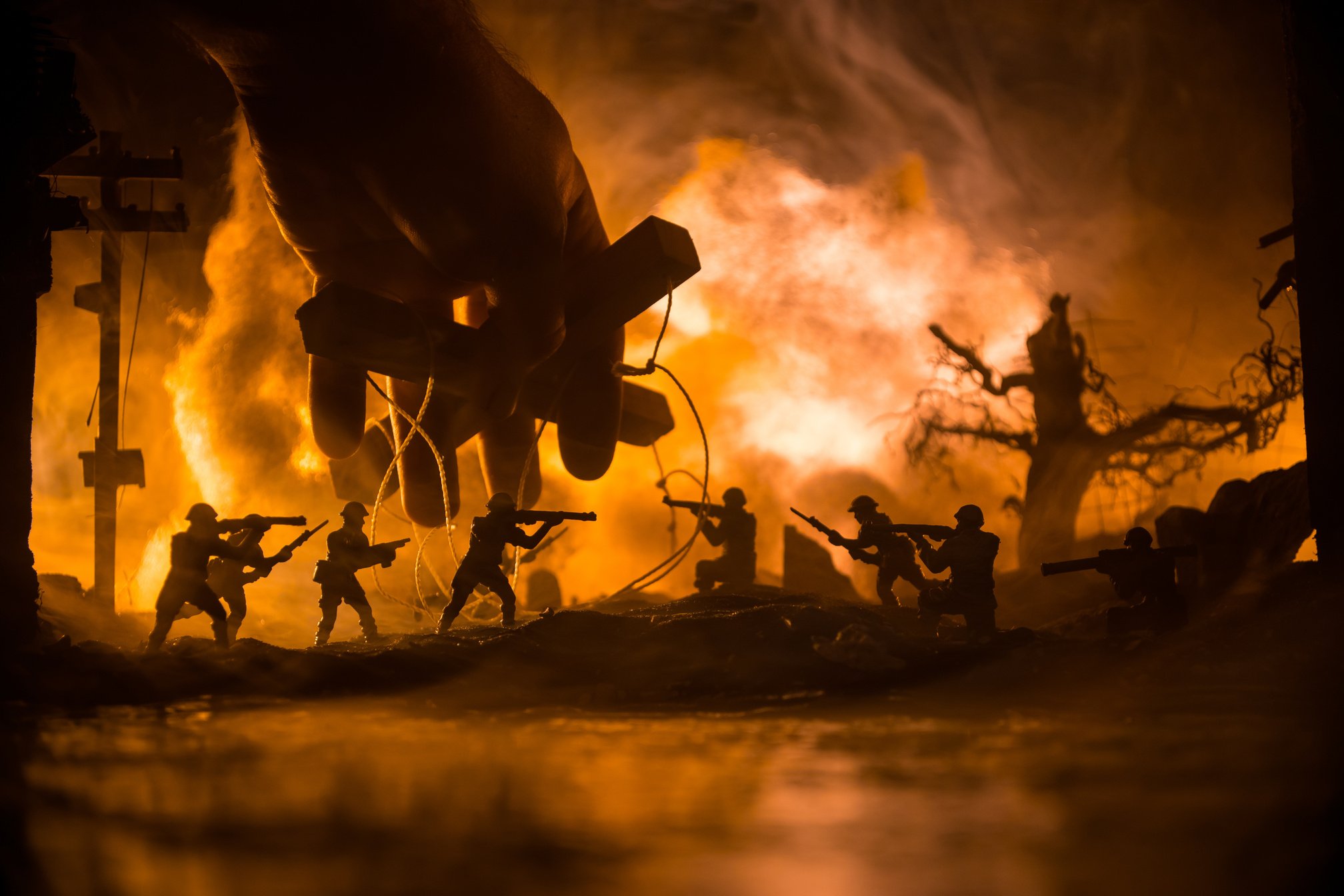 Concept of control. Marionette in human hand. Image on white. Night battle scene. Military fighting silhouettes in destroyed city. Selective focus